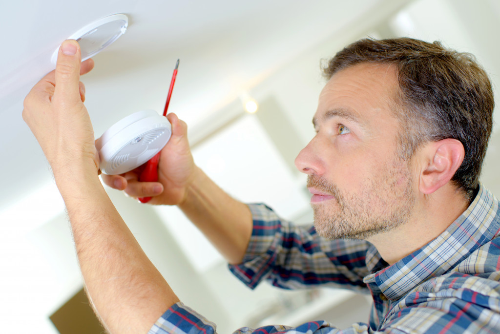 man installing smoke detector in his ceiling