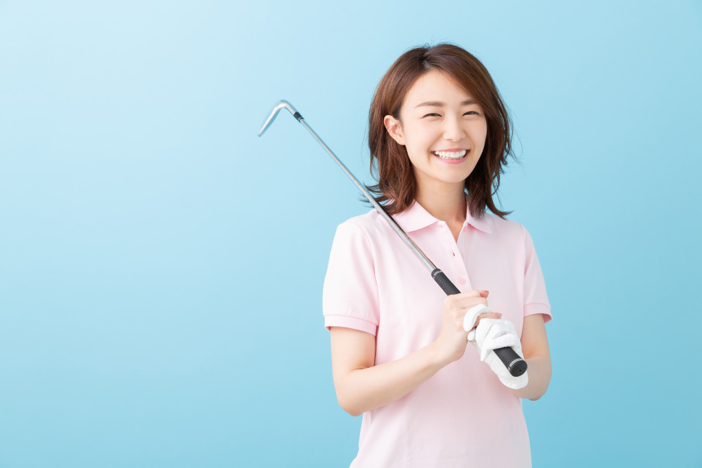young asian woman in pink polo short holding a golf club