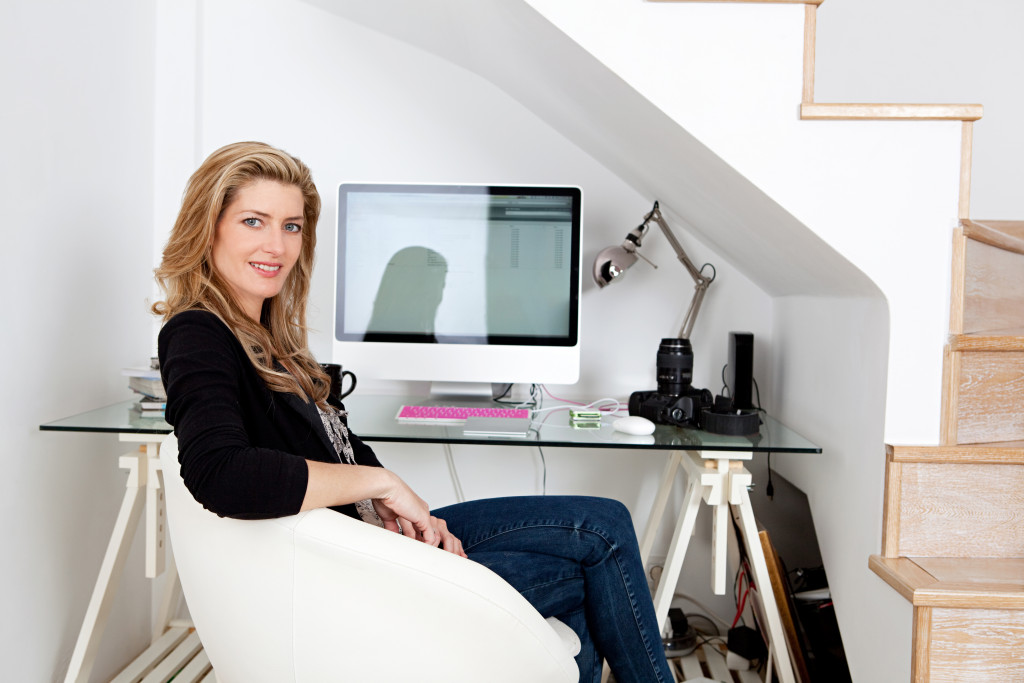 Young professional photographer working from home and sitting at her desk at home, with her camera equipment.