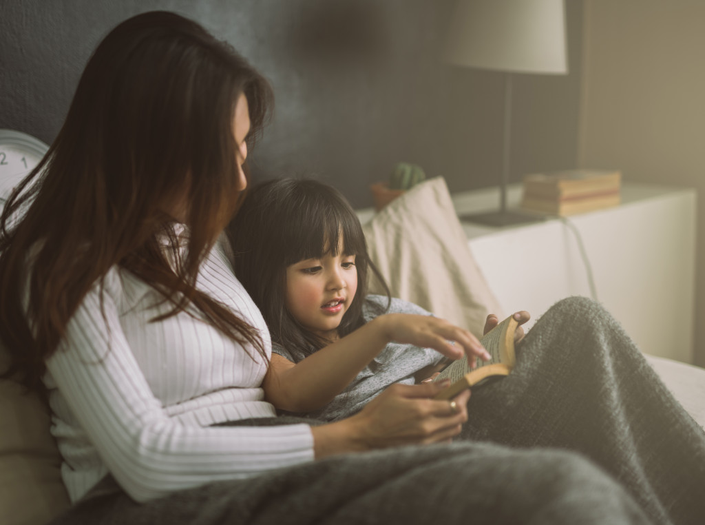 Woman and daughter reading a book in bed. 