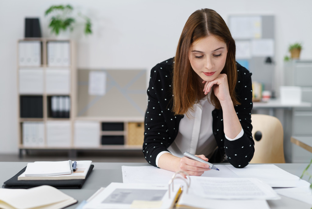 Woman wearing black shrug working in office on papers