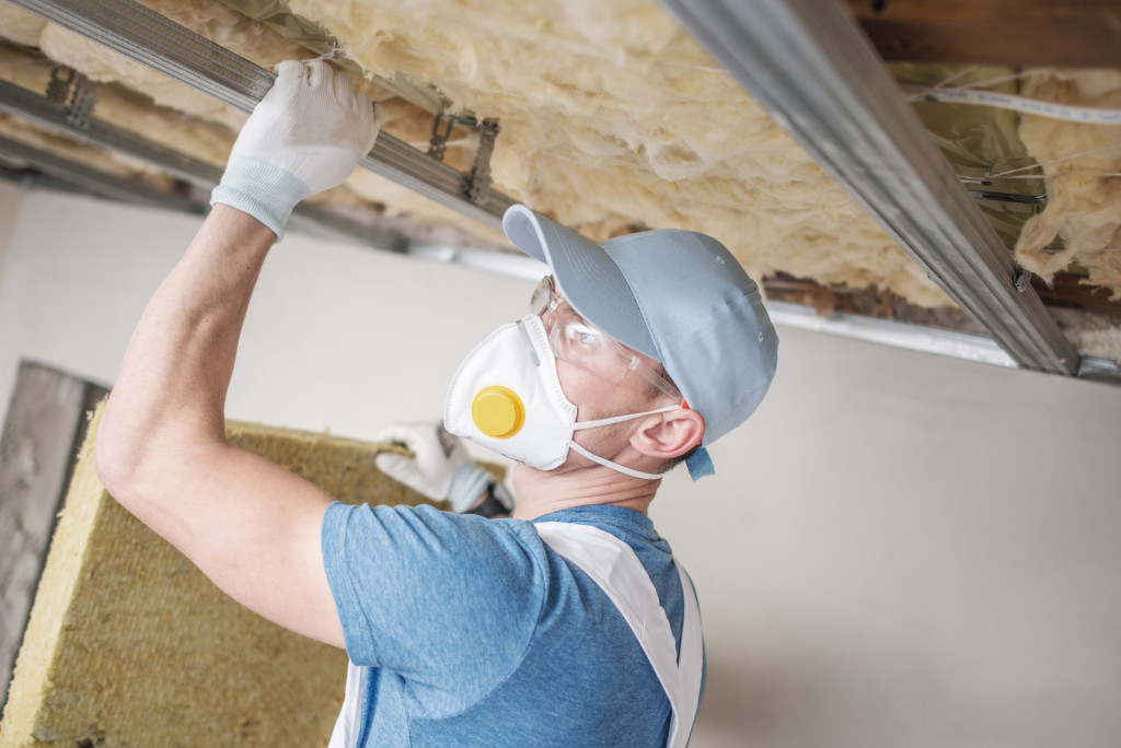 A builder installing insulation on the ceiling