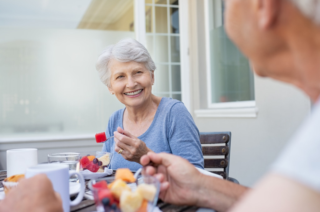 two elderly people eating healthy fruits while smiling
